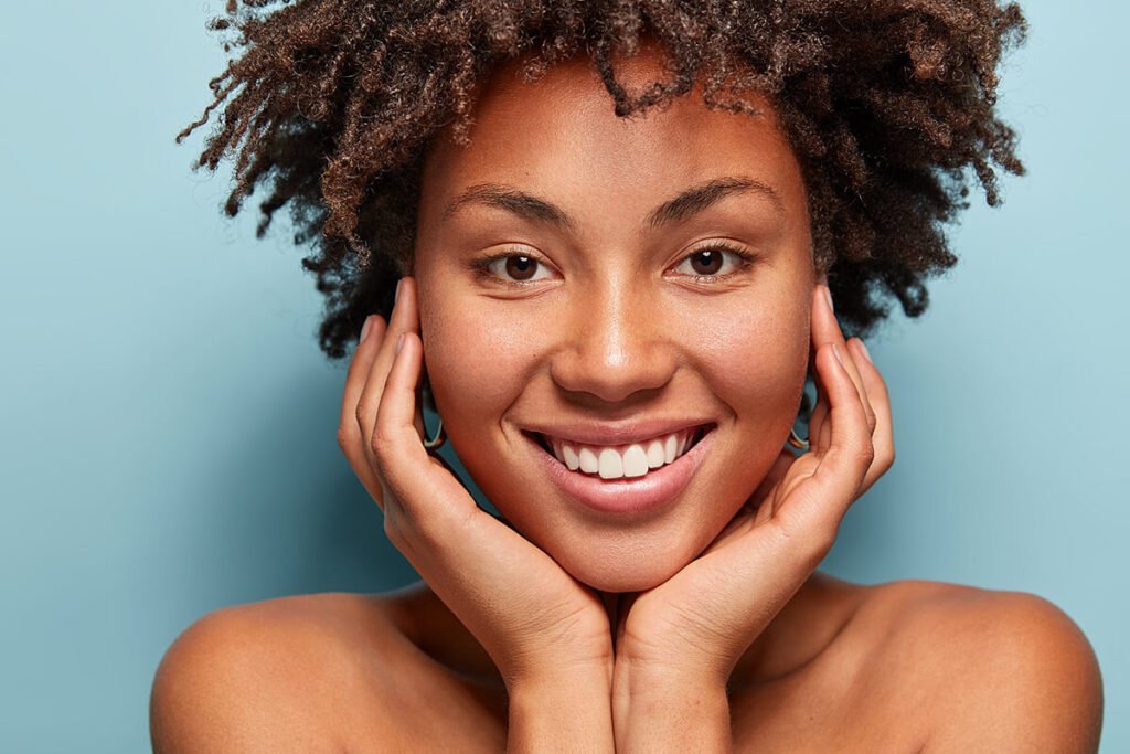 Mulher com pele negra sorrindo para a foto